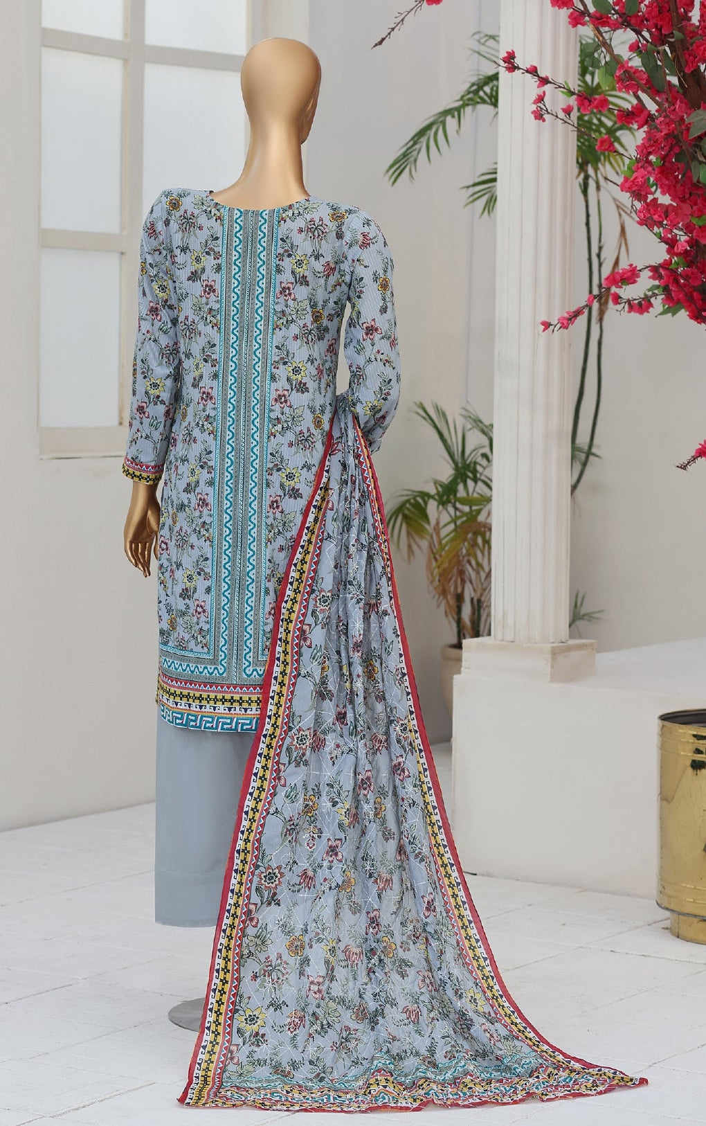 Two mannequins wearing floral dress sets in a decorated room with plants and flowers.