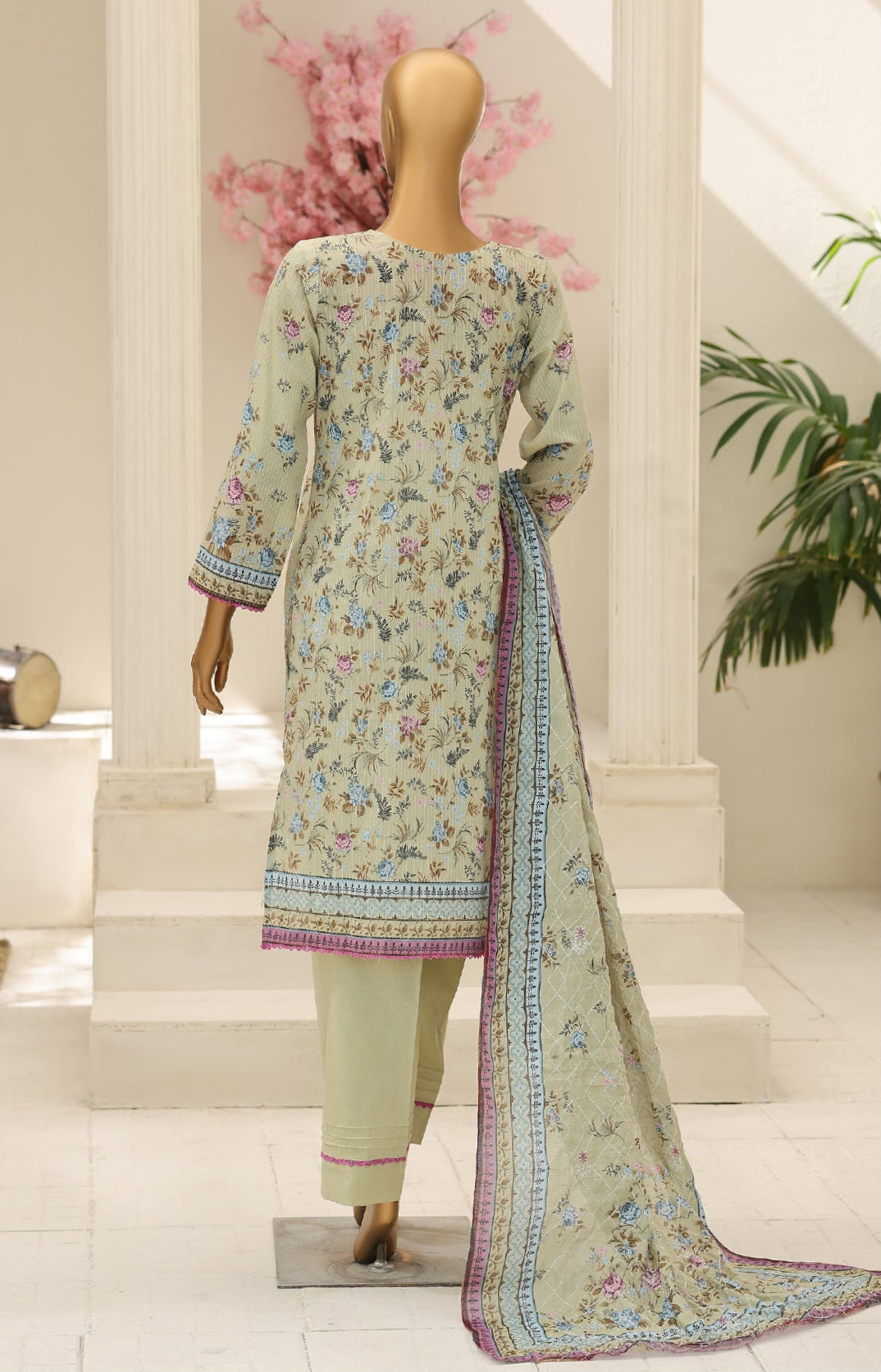 Two mannequins wearing a traditional outfit with floral patterns in a decorative setting.