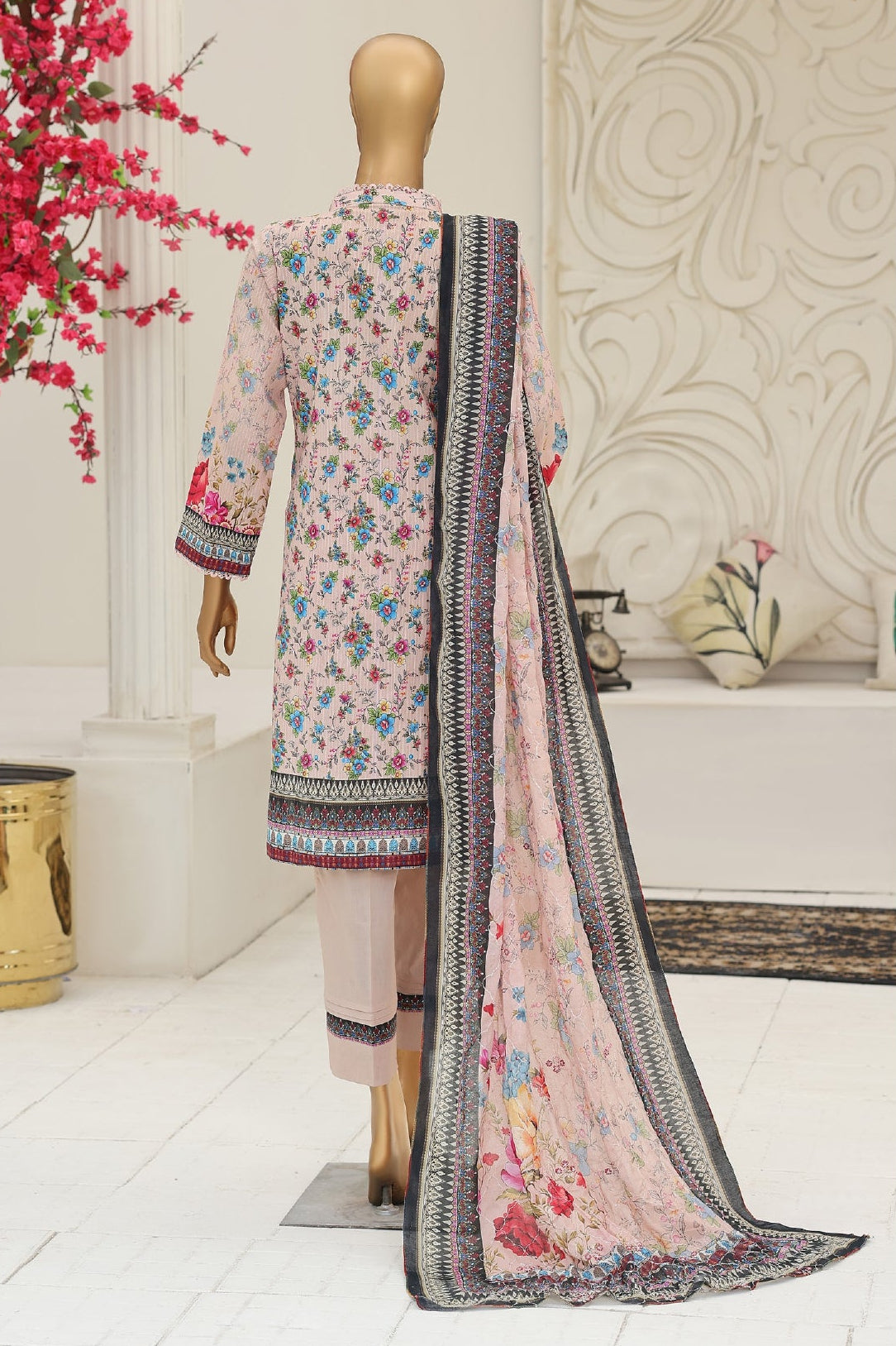 Floral dress with dupatta on a mannequin against a decorative wall.