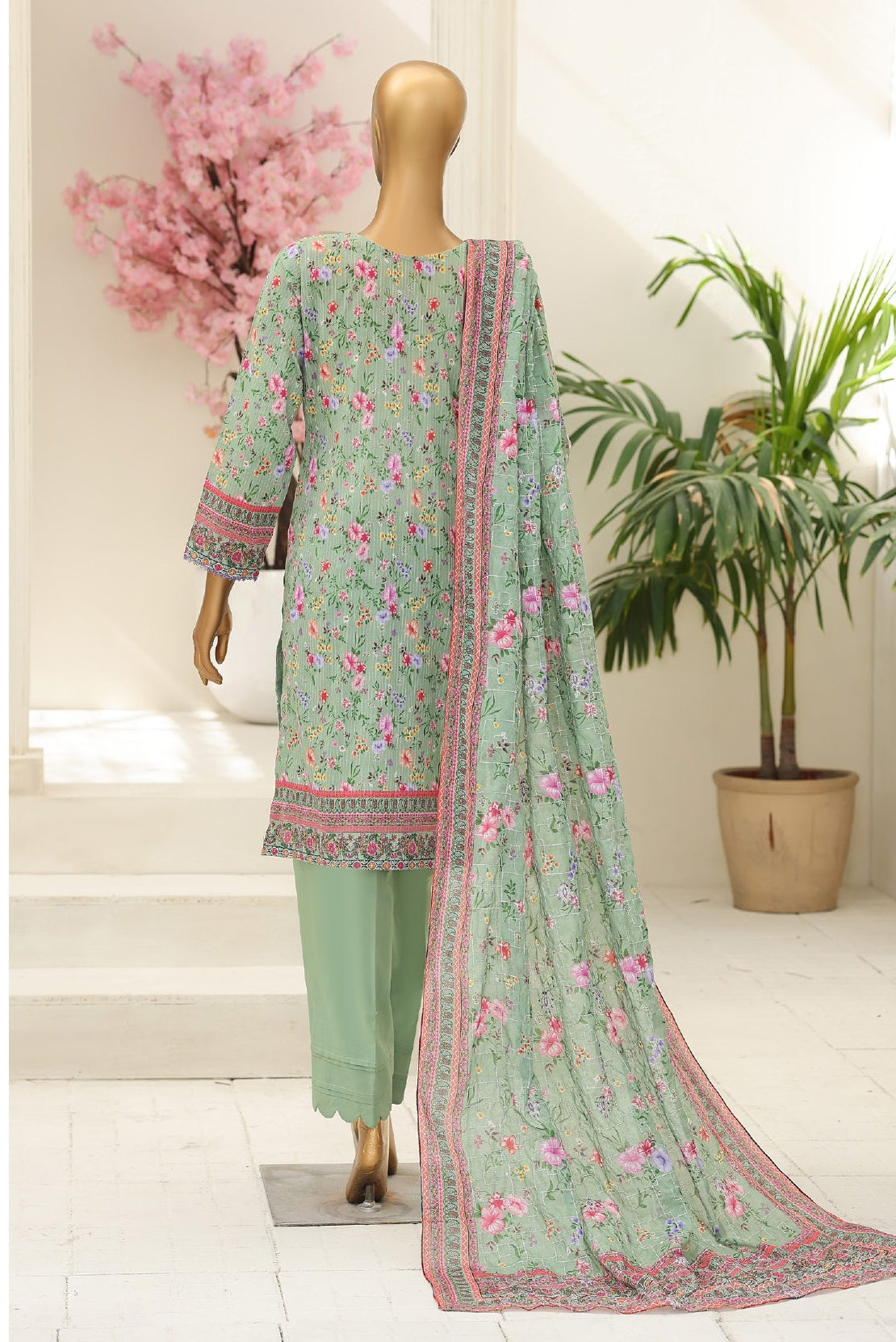 Light green traditional outfit with floral patterns on a mannequin against a neutral background.